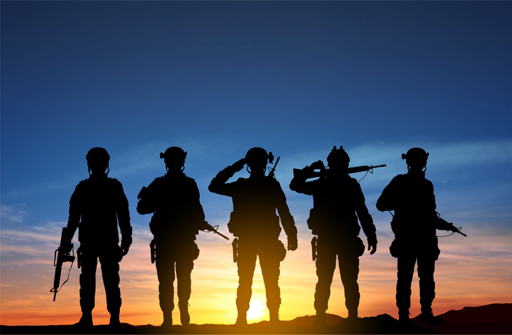 Silhouettes of service members standing together at sunset